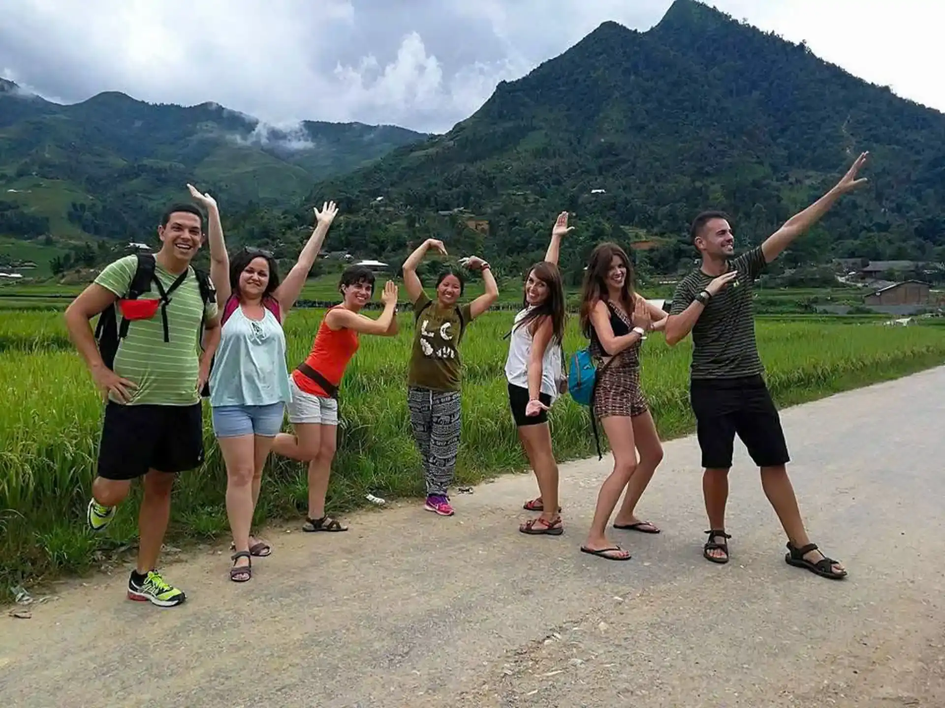 Group of travelers smiling with local Hmong guide in Sapa rice fields